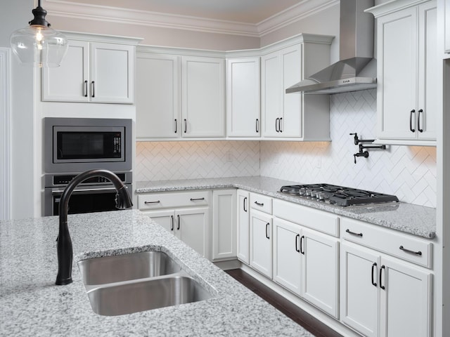 kitchen featuring white cabinets, appliances with stainless steel finishes, pendant lighting, and wall chimney range hood