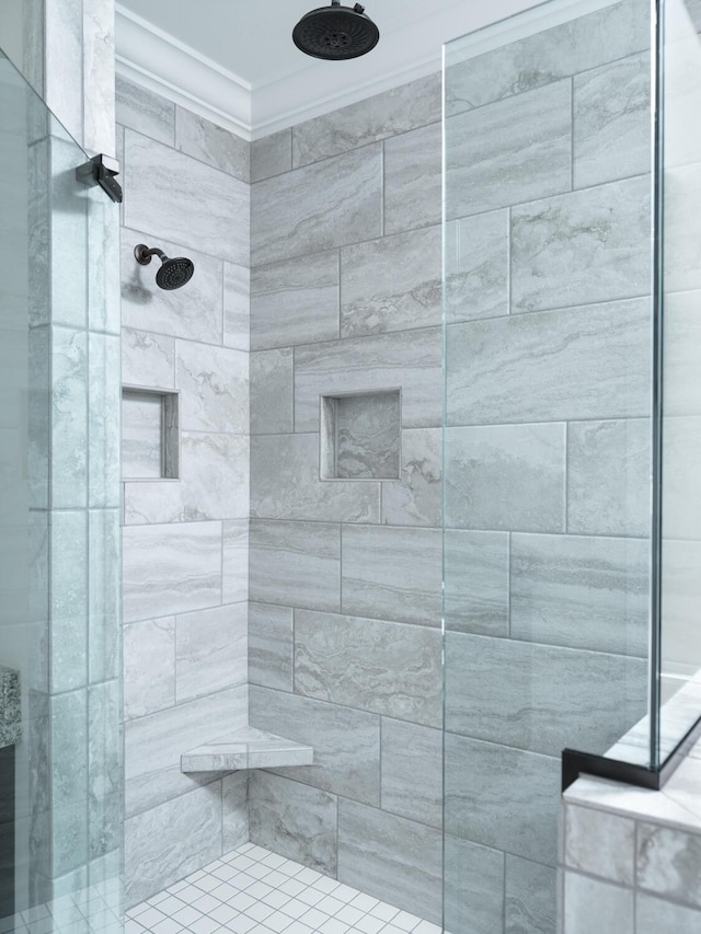 bathroom with a tile shower and crown molding