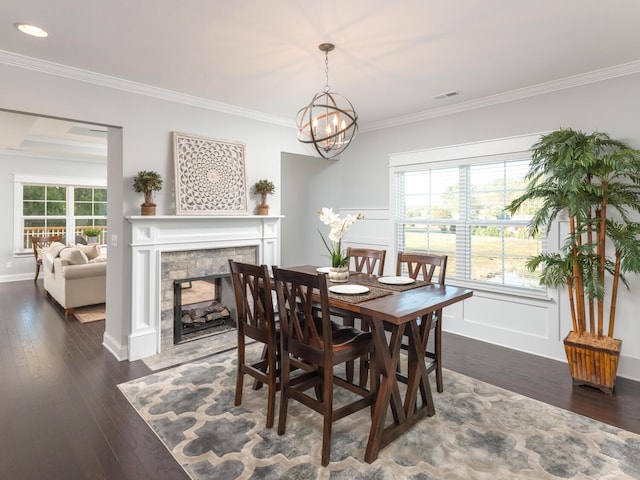 dining room featuring a notable chandelier, crown molding, dark hardwood / wood-style flooring, and a fireplace