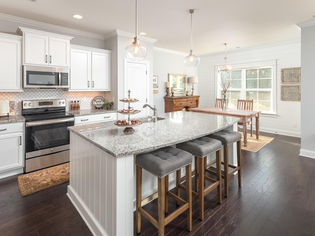 kitchen featuring white cabinets, dark hardwood / wood-style floors, stainless steel appliances, and an island with sink