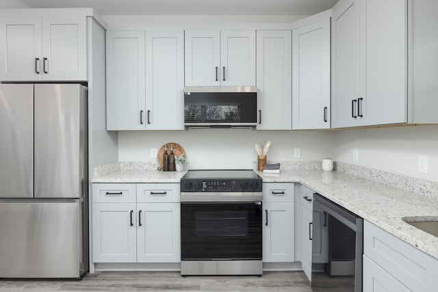 kitchen with wine cooler, light stone counters, white cabinetry, and appliances with stainless steel finishes