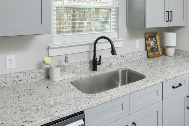 kitchen featuring white cabinetry, light stone counters, and sink