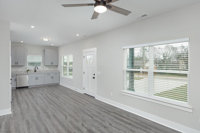 kitchen featuring ceiling fan, sink, light hardwood / wood-style flooring, stainless steel dishwasher, and gray cabinets