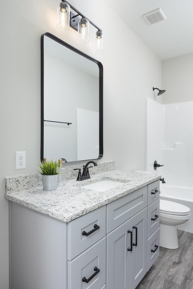 full bathroom with bathtub / shower combination, hardwood / wood-style floors, vanity, and toilet