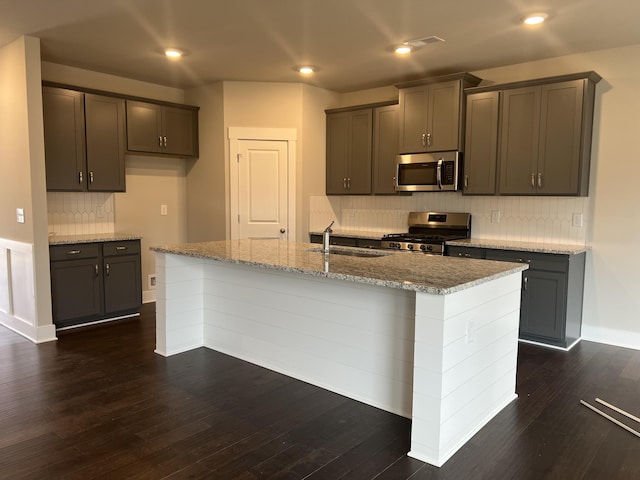 kitchen with a center island with sink, sink, stainless steel appliances, and dark wood-type flooring