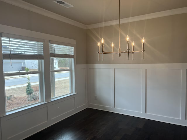 unfurnished dining area featuring dark wood-type flooring, a chandelier, and ornamental molding