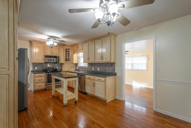 kitchen featuring decorative backsplash, sink, light hardwood / wood-style floors, and appliances with stainless steel finishes