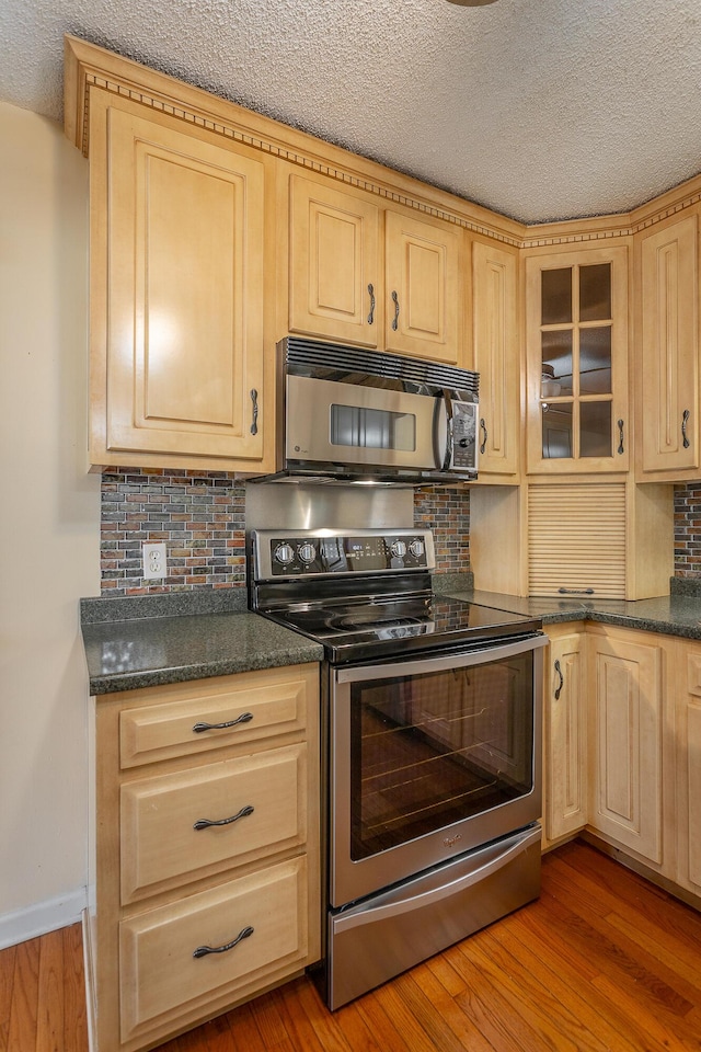 kitchen featuring light brown cabinetry, tasteful backsplash, a textured ceiling, stainless steel electric stove, and light hardwood / wood-style flooring