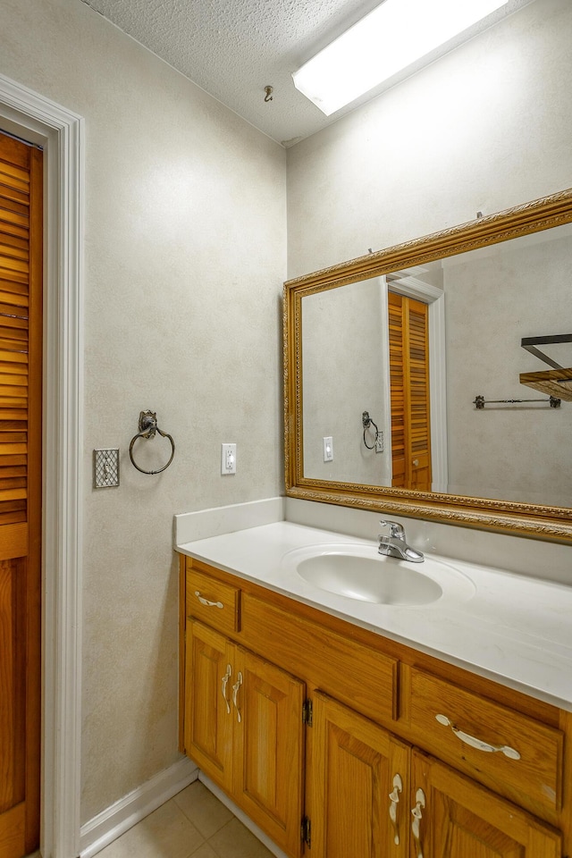 bathroom with tile patterned flooring, vanity, and a textured ceiling