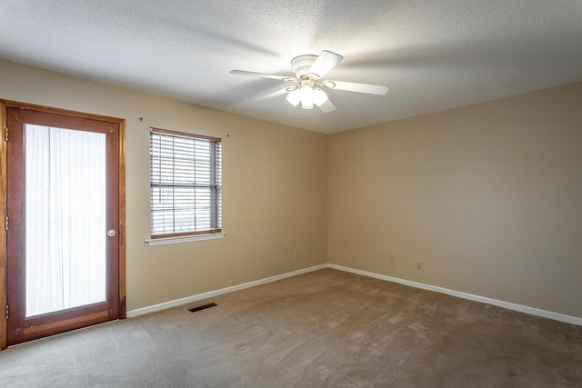 carpeted empty room featuring ceiling fan and a textured ceiling