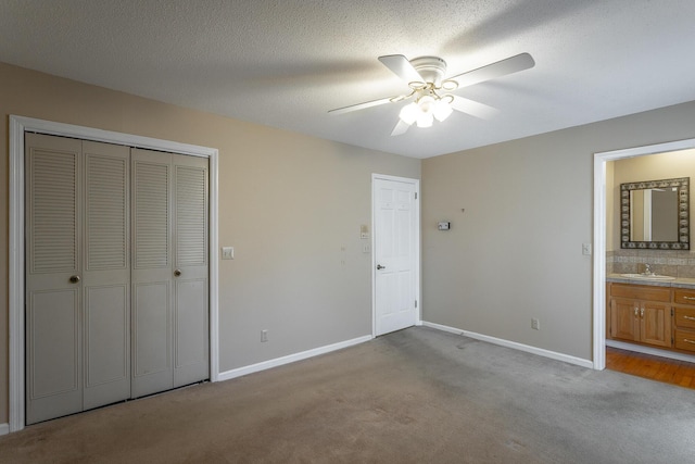 unfurnished bedroom with a closet, ceiling fan, sink, and light colored carpet