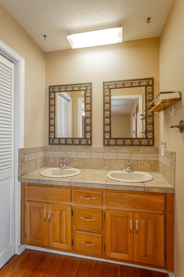 bathroom with vanity, a textured ceiling, hardwood / wood-style flooring, and tasteful backsplash