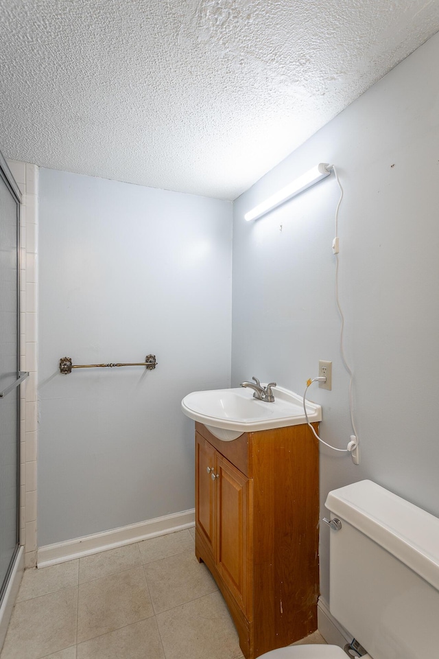 bathroom with an enclosed shower, vanity, toilet, and a textured ceiling