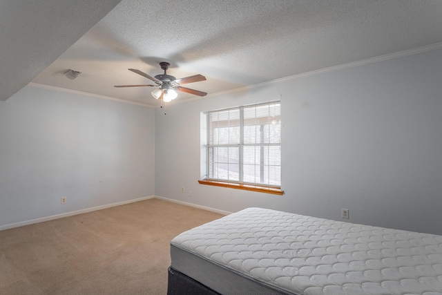 bedroom with ceiling fan, crown molding, light colored carpet, and a textured ceiling