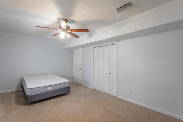 carpeted bedroom featuring a textured ceiling, a closet, ceiling fan, and crown molding