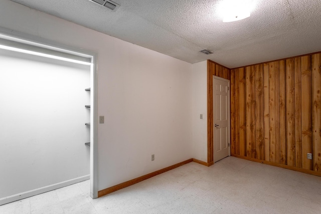 unfurnished bedroom featuring wood walls and a textured ceiling