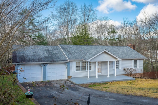 ranch-style home featuring covered porch, a front yard, and a garage