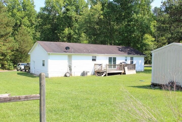 rear view of house with a lawn, a storage unit, and a wooden deck