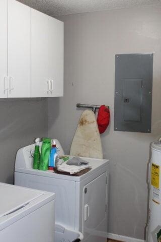 laundry room with washing machine and clothes dryer, cabinets, water heater, electric panel, and a textured ceiling