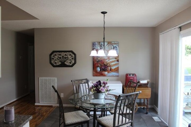 dining area with dark hardwood / wood-style flooring, a textured ceiling, and an inviting chandelier