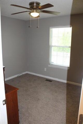 carpeted spare room featuring ceiling fan