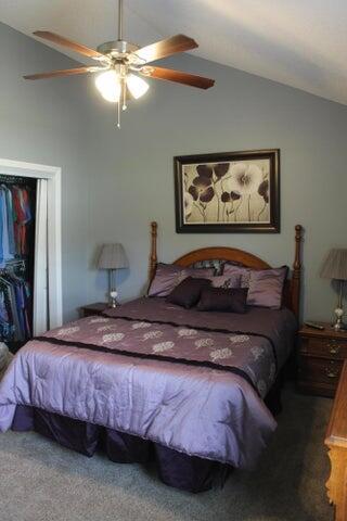 bedroom featuring carpet flooring, a closet, lofted ceiling, and ceiling fan