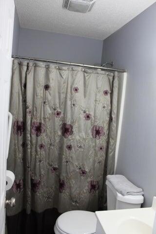 bathroom featuring curtained shower, a textured ceiling, and toilet