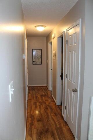 hall with a textured ceiling and dark wood-type flooring