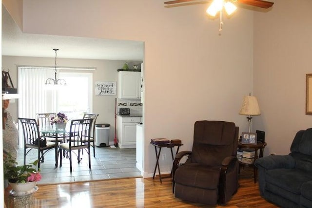 living room featuring ceiling fan with notable chandelier and hardwood / wood-style flooring