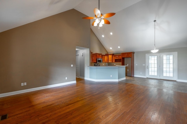 unfurnished living room with ceiling fan, high vaulted ceiling, visible vents, baseboards, and dark wood finished floors