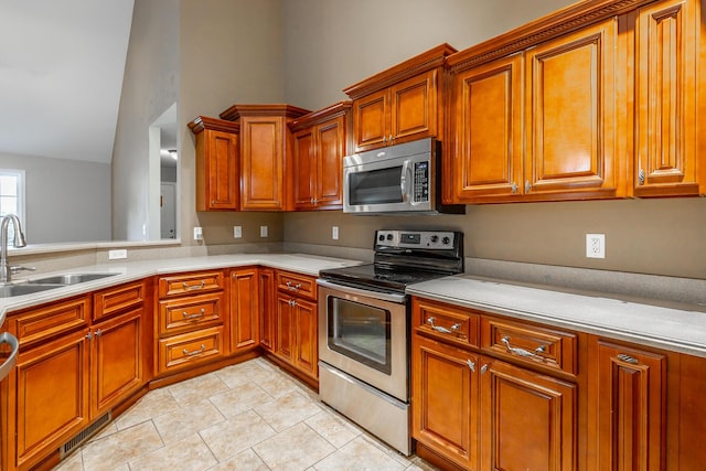 kitchen featuring lofted ceiling, stainless steel appliances, a sink, and light countertops