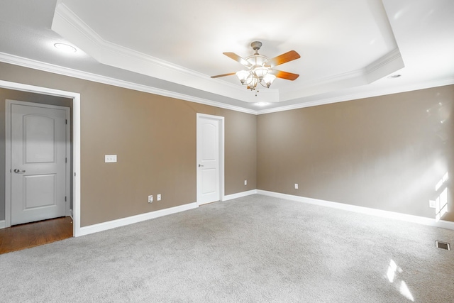 empty room with a ceiling fan, a raised ceiling, crown molding, and baseboards