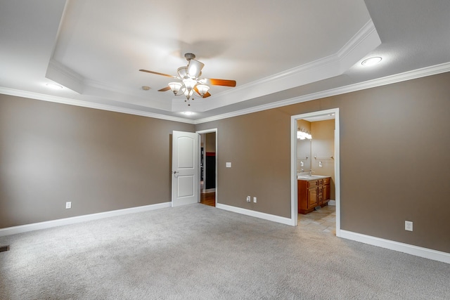 unfurnished bedroom with light carpet, a tray ceiling, and baseboards