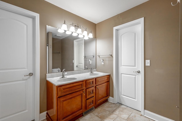 bathroom with visible vents, double vanity, a sink, and toilet