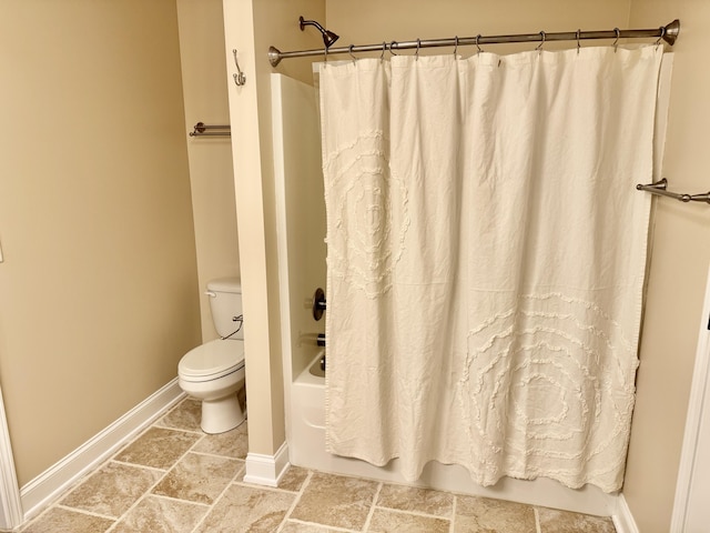 full bathroom with baseboards, stone finish flooring, toilet, and shower / tub combo with curtain