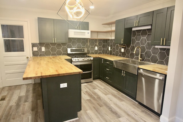 kitchen with butcher block counters, sink, stainless steel appliances, backsplash, and ornamental molding