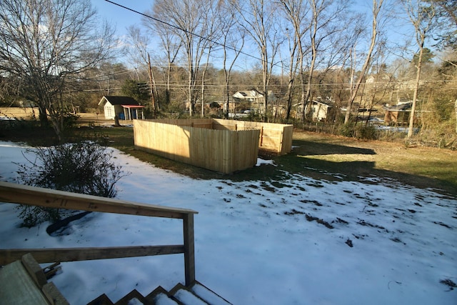 yard layered in snow featuring a storage shed