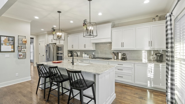 kitchen featuring sink, stainless steel appliances, light stone counters, an island with sink, and white cabinets