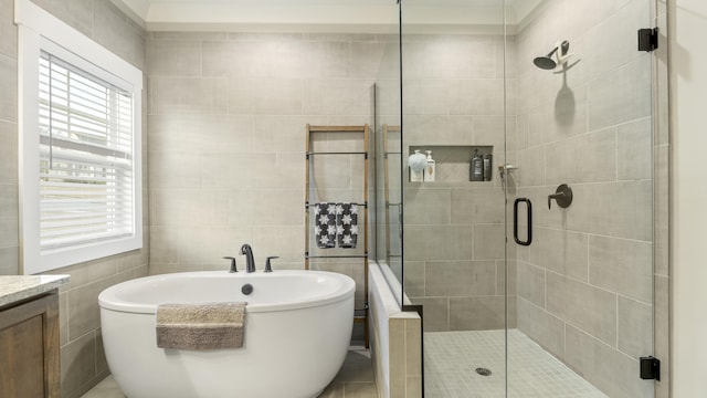 bathroom with separate shower and tub, vanity, and tile walls