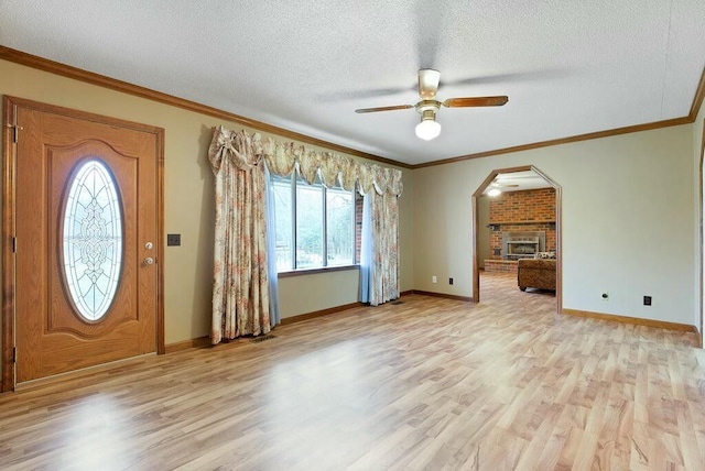 foyer entrance with ceiling fan, crown molding, light wood-type flooring, and a textured ceiling