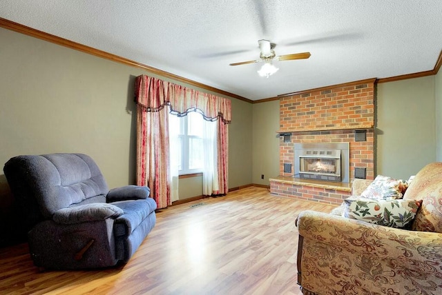 living room with a textured ceiling, light hardwood / wood-style flooring, ceiling fan, and crown molding