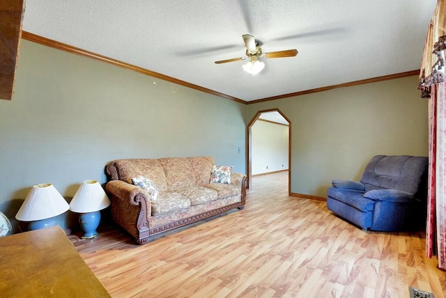 living room featuring ceiling fan, crown molding, light hardwood / wood-style floors, and a textured ceiling