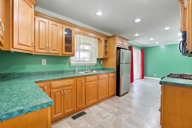 kitchen with stainless steel refrigerator, crown molding, and sink