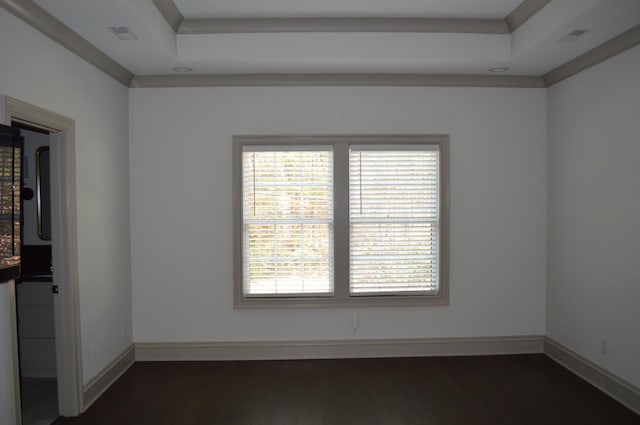 empty room featuring a tray ceiling, crown molding, and dark wood-type flooring