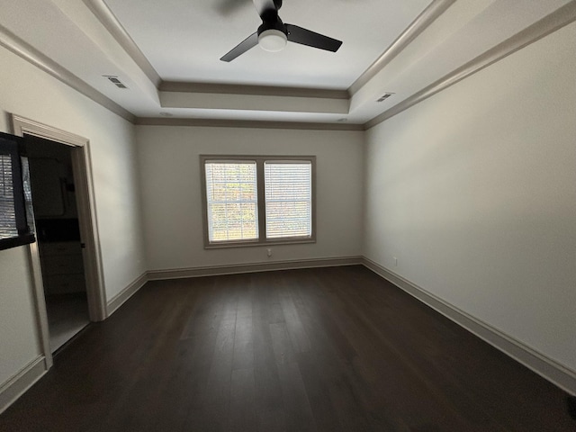 spare room with a raised ceiling, ceiling fan, and dark wood-type flooring