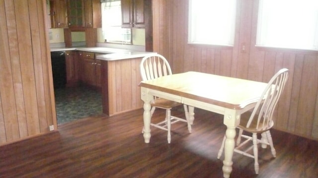 dining space with dark hardwood / wood-style floors, a healthy amount of sunlight, and wood walls