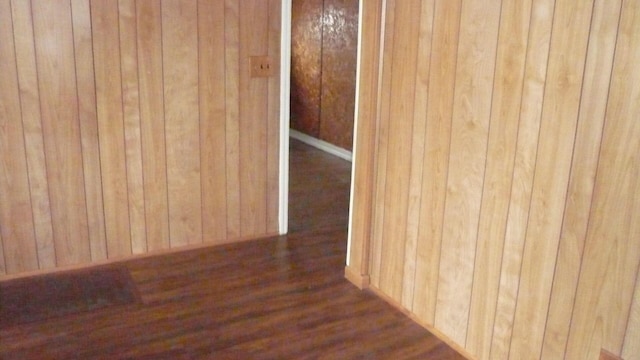 spare room featuring wooden walls and dark wood-type flooring