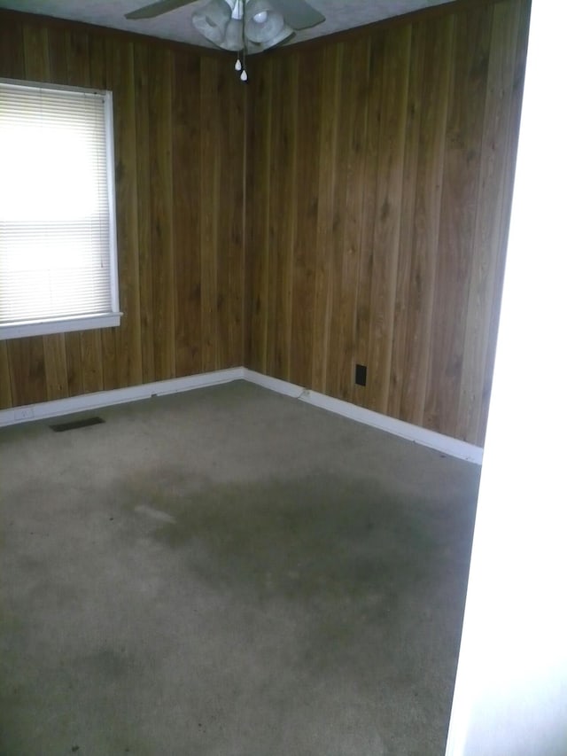 spare room with ceiling fan and wooden walls