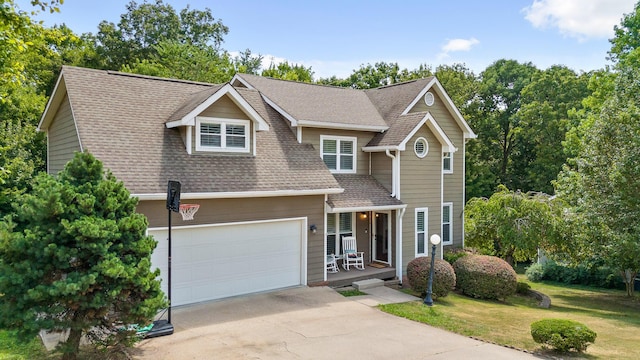 view of front of property with covered porch, a garage, and a front lawn