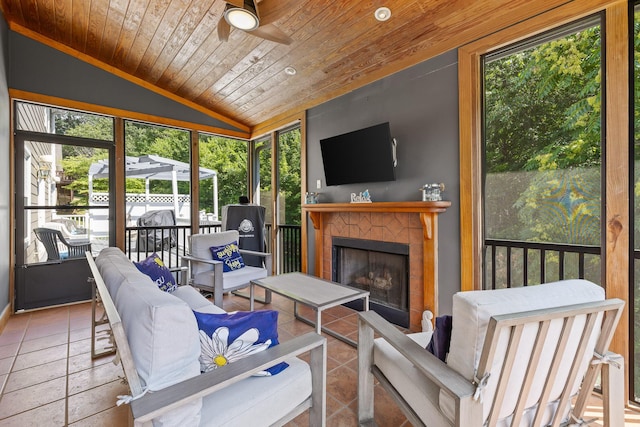 sunroom featuring a fireplace, vaulted ceiling, ceiling fan, and wood ceiling